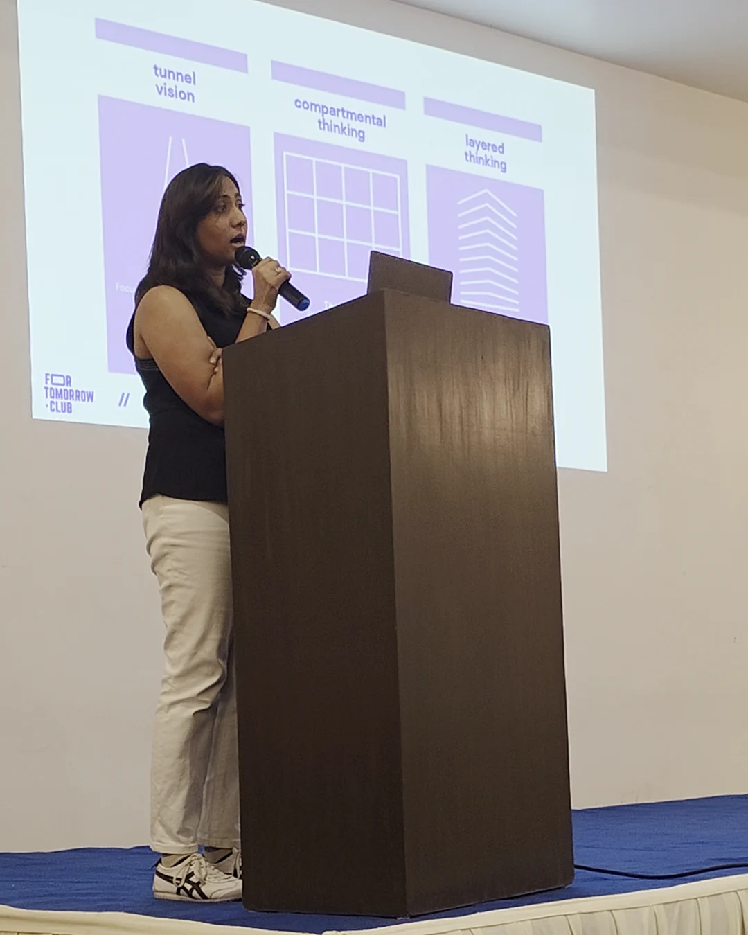 Isha on the mic, presenting at For Tomorrow Club